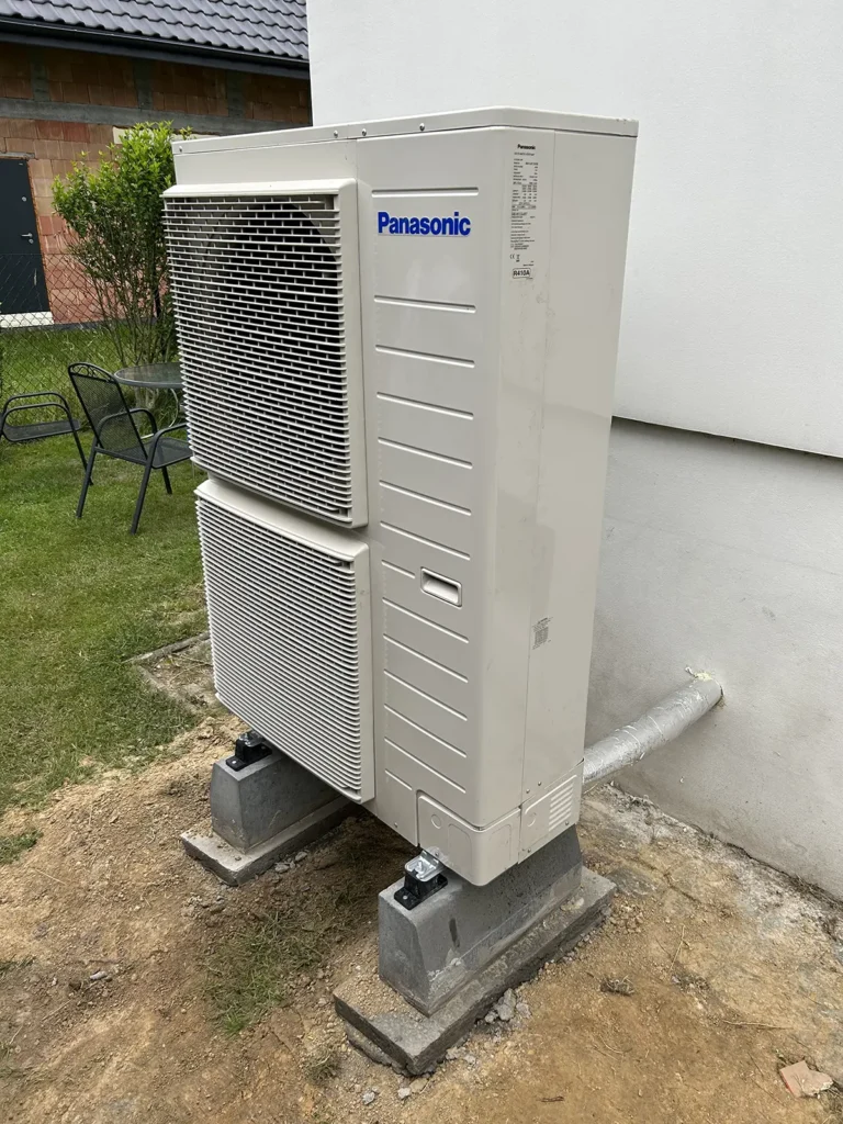 Zewnętrzna jednostka pompy ciepła Panasonic T-CAP 12 kW zainstalowana na podmurówce obok budynku w Radlinie.