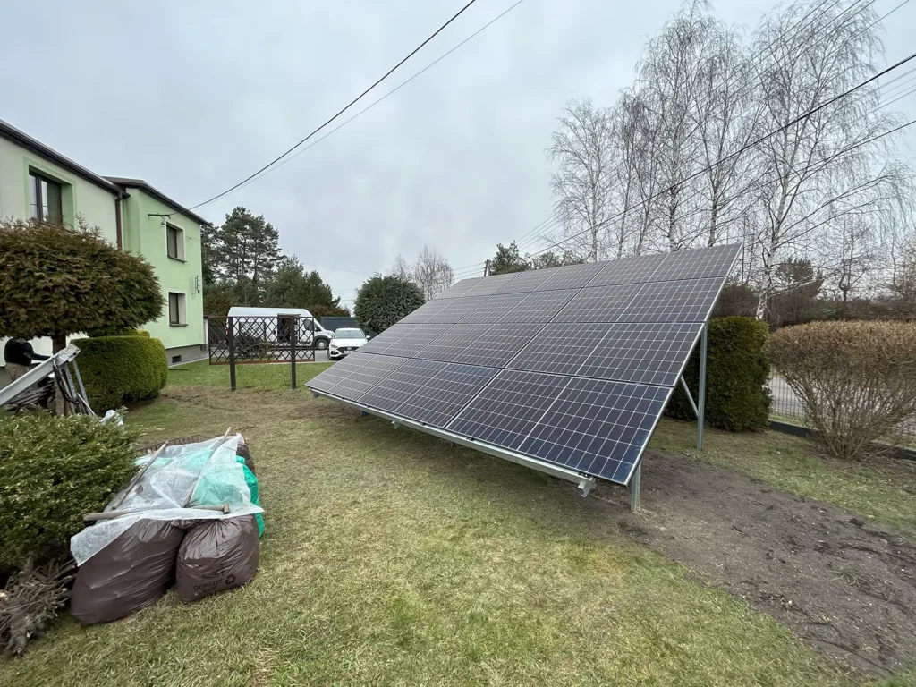 Widok boczny naziemnej instalacji fotowoltaicznej o mocy 5,760 kWp w Wodzisławiu Śląskim, w tle budynki mieszkalne.